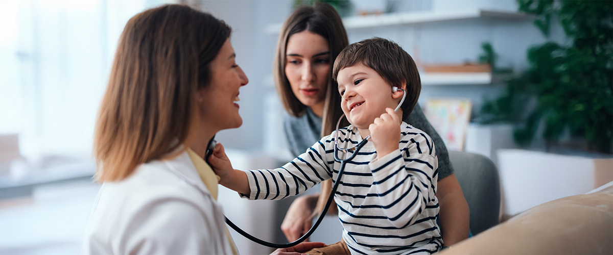 Small child in a physician's office, playing with a stethoscope.