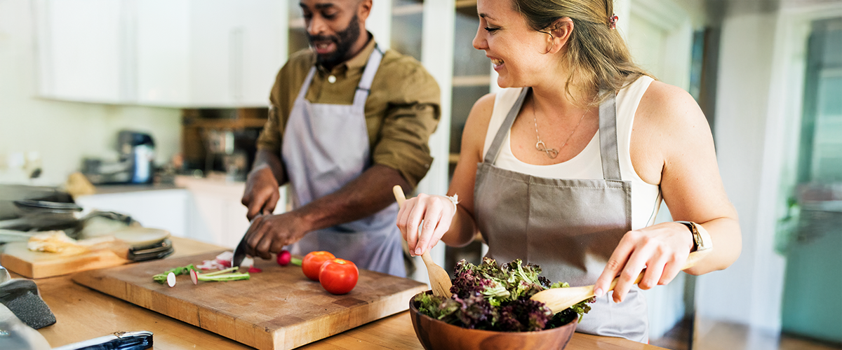 A couple cooking a meal together in a kitchen.
