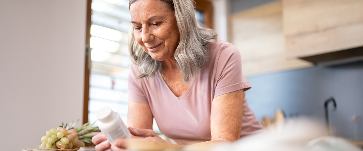 Woman at home, reading the label of bottle of medication.