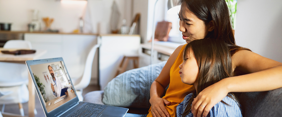 Mother and daughter attending a telehealth appointment on a laptop.